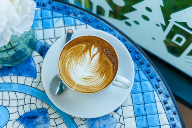 Café con leche caliente con espuma de leche de arte latte en una taza en el escritorio del piso de mármol Como desayuno En una cafetería en el café durante el concepto de trabajo de negocios