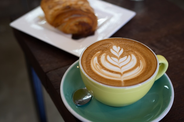 café con leche caliente con hermoso arte de la espuma en la mesa de cristal.