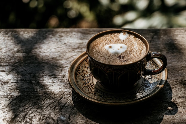 Café con leche caliente en una taza sobre una mesa de madera vintage.