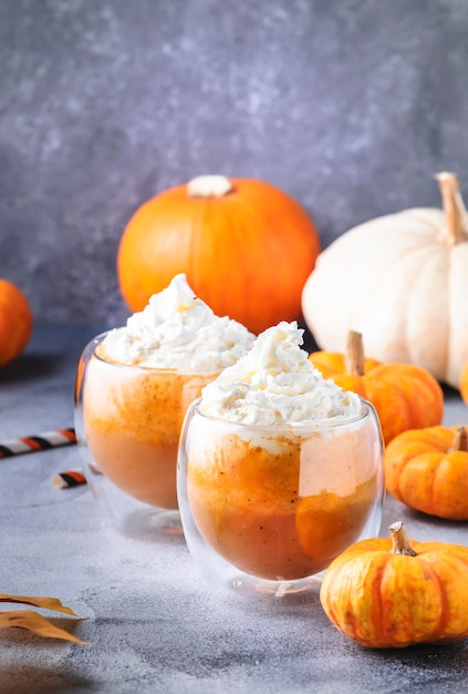 Café con leche con especias de calabaza o café en taza de vidrio doble sobre mesa gris Bebida caliente de otoño o invierno en una mesa festiva