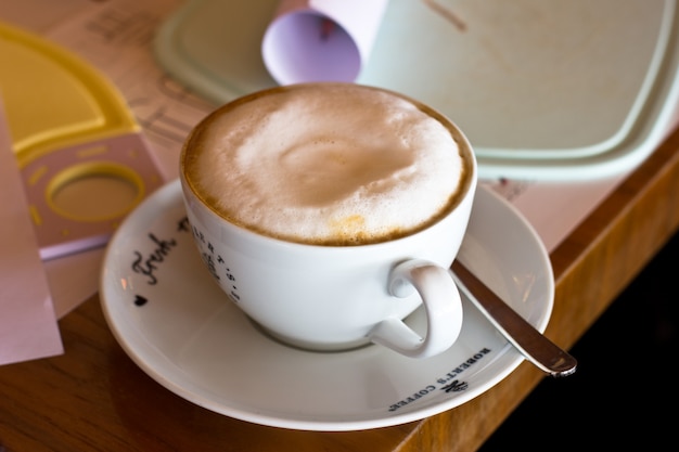 Café con leche con espuma en una taza blanca sobre la mesa