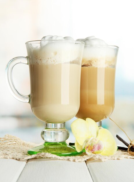 Café con leche fragante en vasos con especias en la mesa de madera