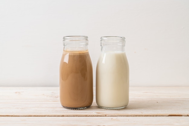 café y leche fresca en botella sobre madera