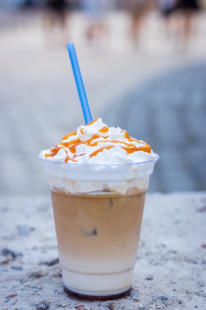 Café con leche frío con crema batida y pajita para beber Café con leche helado decorado con topping de caramelo salado