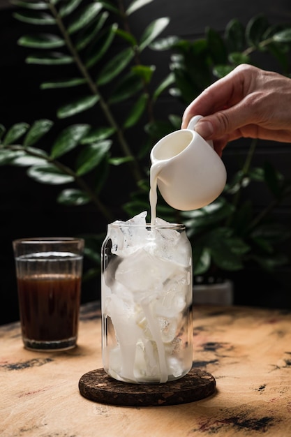 Café con leche helado frío en preparación Un vaso alto lleno de cubitos de hielo Una jarra de leche Espresso en el vaso