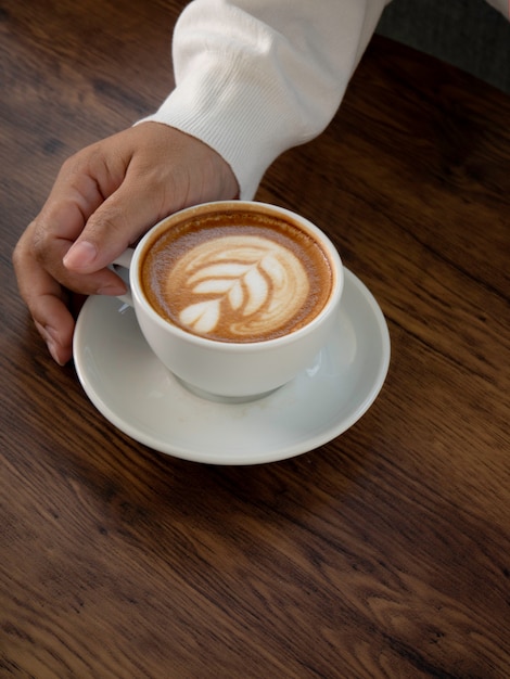 Café con leche con hermoso arte con leche en la mano