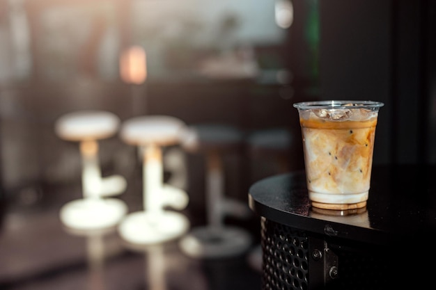 Café con leche con hielo en vaso de plástico sobre la mesa negra en el café