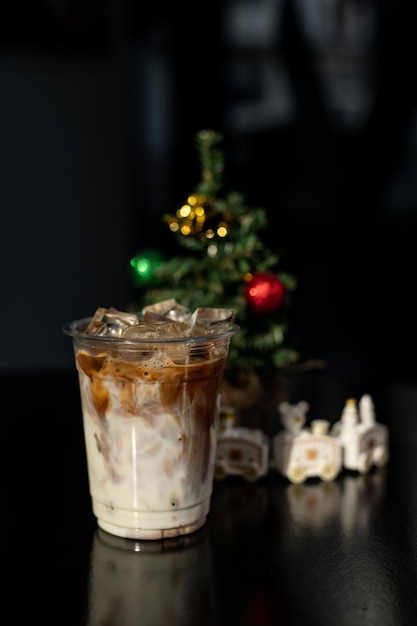 Café con leche con hielo en vaso de plástico sobre la mesa negra en el café