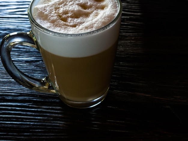 Café con leche en la mesa de madera negra cerca de la ventana