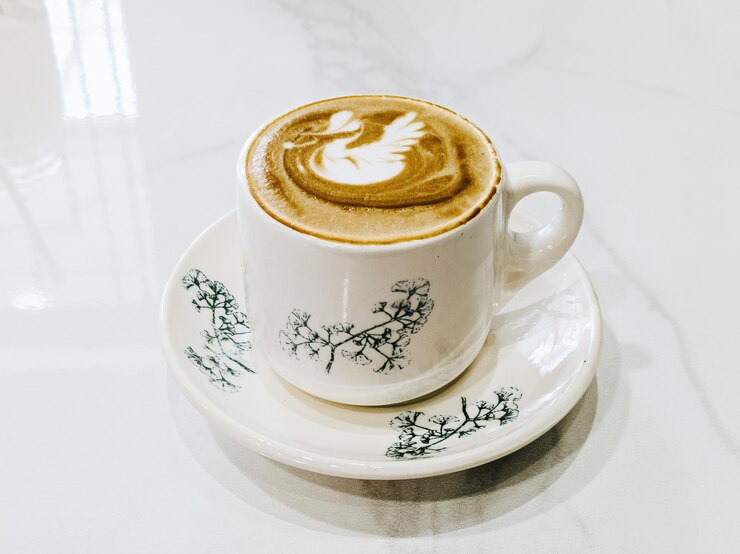 Café con leche minimalista en la taza y el plato de estilo Kopitiam y en la mesa blanca