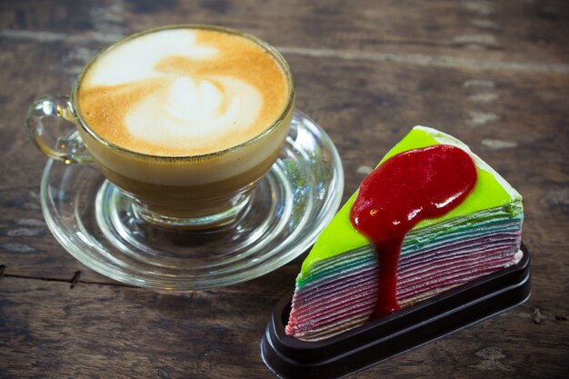 café con leche y pastel de crepé de arcoiris con salsa de fresa