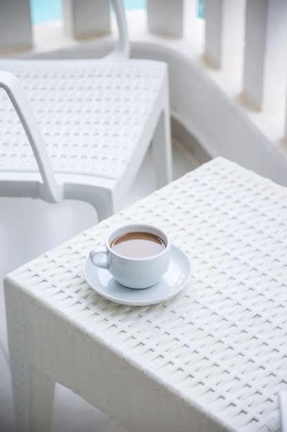 Café con leche en una taza blanca en el balcón del hotel.