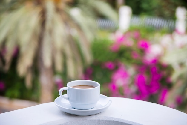 Café con leche en una taza blanca en el balcón del hotel.