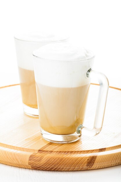 Foto café con leche en tazas de vidrio en el tablero