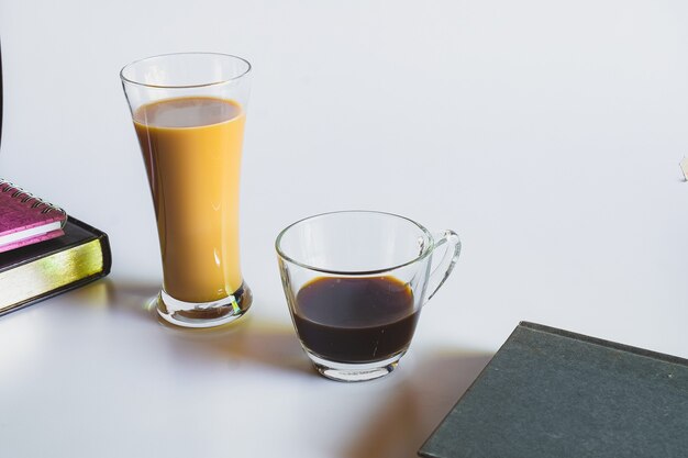 Café con leche en vaso alto y café negro, estilo rústico y refrescante.