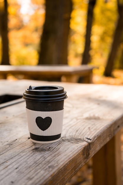 Café para llevar con forma de corazón sobre vidrio, concepto de otoño. Foto de alta calidad