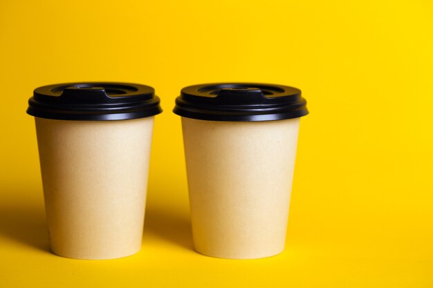 Café para llevar. taza de papel con café sobre un fondo amarillo.