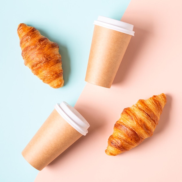 Café para llevar en un vaso de papel con croissants vista superior