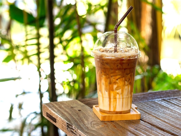 Café macchiato de caramelo helado sobre una mesa de madera con fondo natural