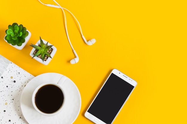 Café de la mañana, cuaderno, teléfono móvil, plantas en amarillo