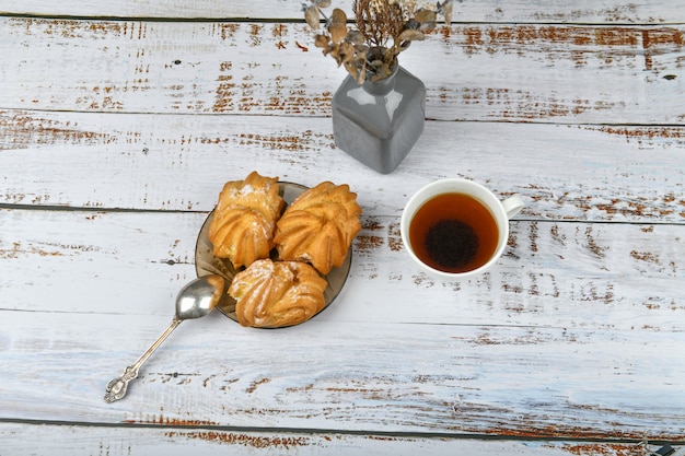 Café de la mañana con dulces. con relleno de crema. aplanada en una mesa de madera clara.