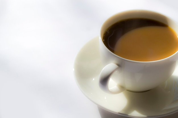 Café de la mañana en una taza blanca sobre un platillo blanco