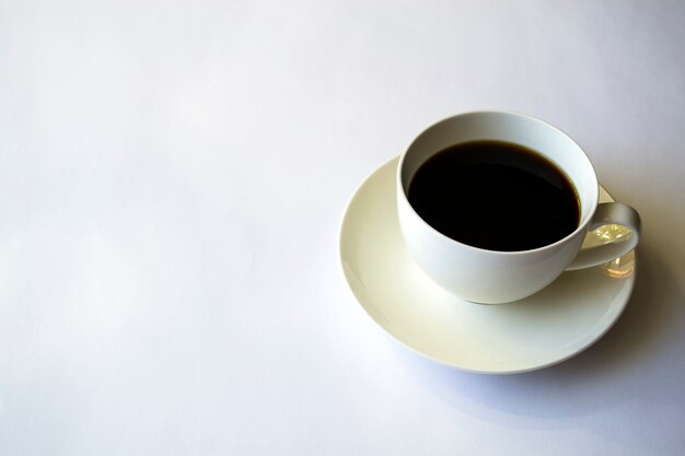 Café de la mañana en una taza blanca sobre un platillo blanco