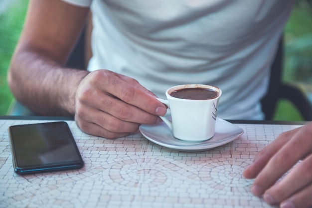 Café de mano de hombre con teléfono