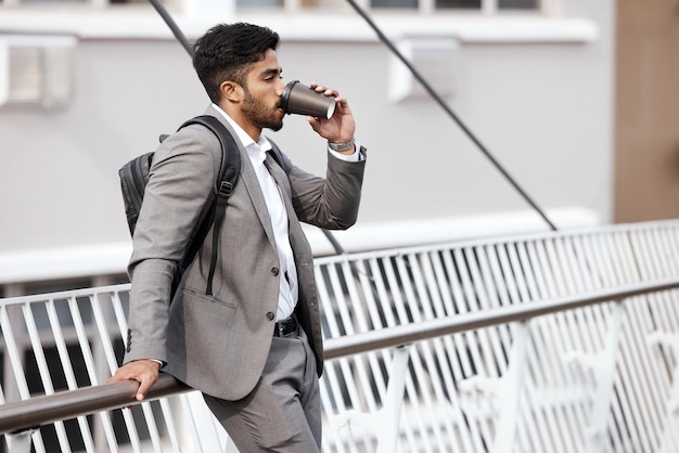 El café mantiene mi energía Toma de un joven hombre de negocios bebiendo una taza de café en la ciudad