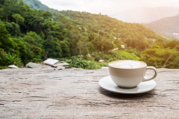 Foto café en la mesa de madera con vista a la montaña