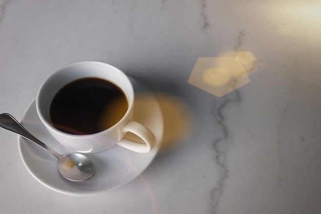 Café en la mesa de mármol con la luz de la llamarada