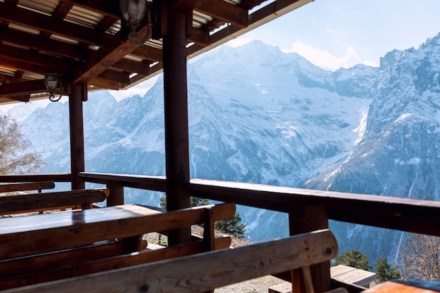 Un café con mesas y bancos de madera en las montañas nevadas con una hermosa vista panorámica. Turismo y deporte.