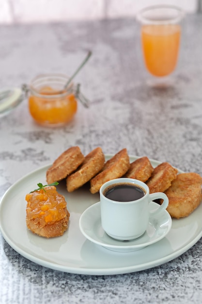 Café con migas de pan y mermelada sobre un fondo gris