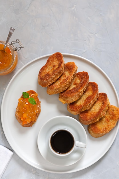 Café con migas de pan y mermelada sobre un fondo gris