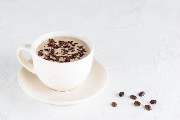 Café moccachino con nueces y chocolate sobre un fondo claro.