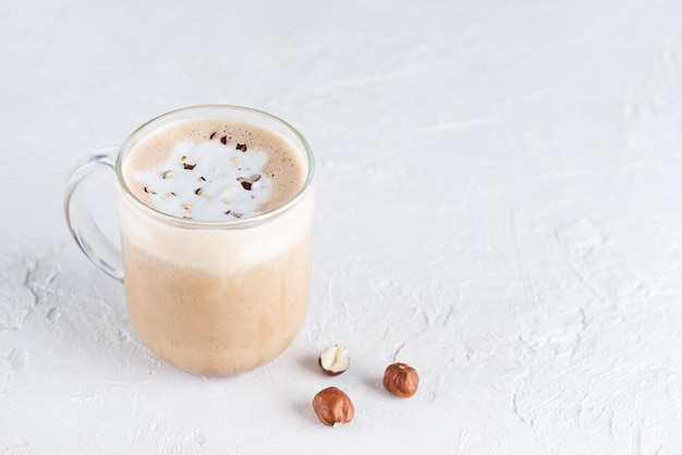 Café mochaccino de nozes em uma caneca de vidro em uma mesa de luz. Orientação horizontal, espaço de cópia.