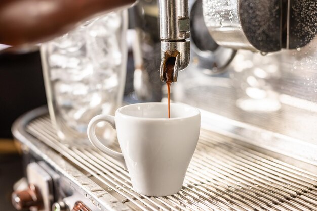 Café moído com um copo de cubos de gelo, um barista prepara uma bebida de café