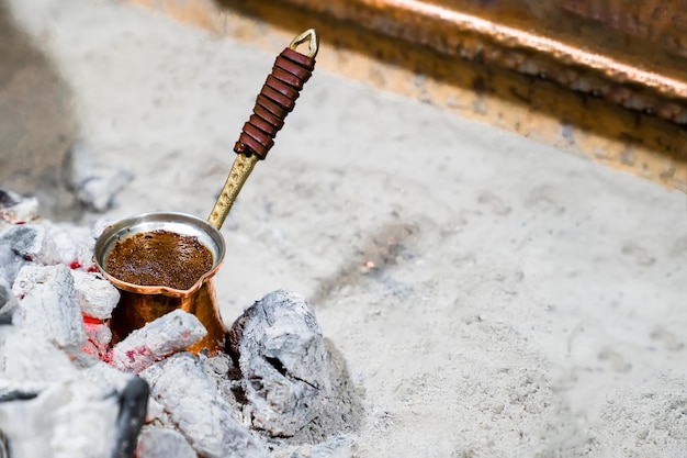 El café molido natural se elabora en turco de cobre sobre carbón según la tradición turca, espacio de copia