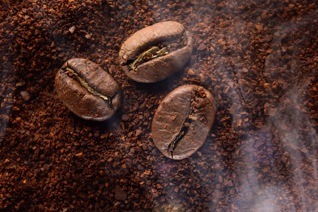 Café molido y tres frijoles en un ligero humo.