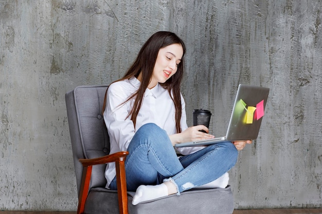 Café de la mujer joven en su mano que trabaja en la computadora portátil. foto de alta calidad