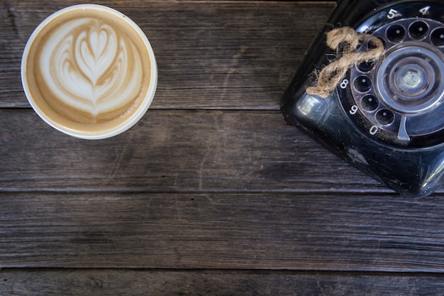 Café na mesa de madeira com telefone antigo