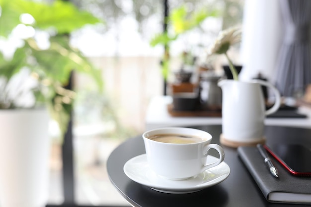 Café na xícara de cerâmica e notebook na mesa de madeira preta