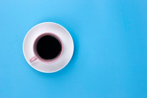 Un café negro aislado en un cachorro rosa claro sobre fondo azul claro