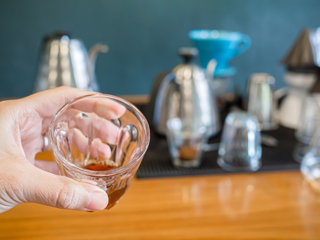 Foto el café negro caliente se extrae del proceso de goteo en un trago de espresso en la mano por un hombre.