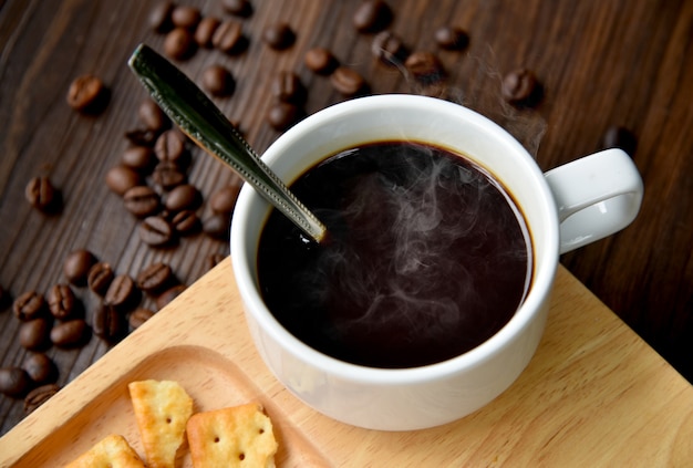 Café negro caliente en una taza con núcleo de Crackers.