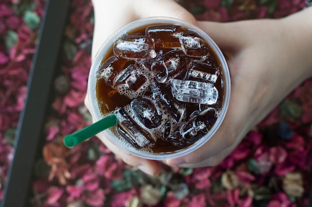 Café negro frío en una taza y mano de mujer