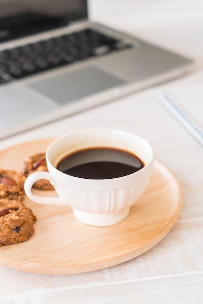 Café negro y galletas con laptop y cuaderno.