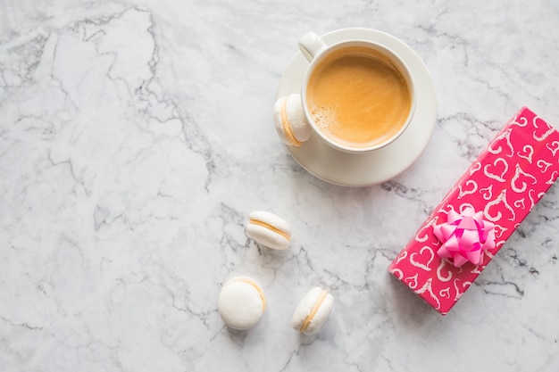 café negro con galletas de macarrones, caja presente. Taza de café y macarrones de colores. Macarrones dulces.