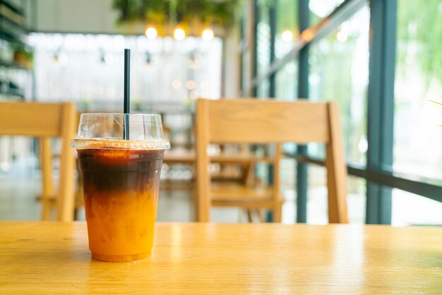 Café negro helado con taza de jugo de yuzu de naranja en la mesa en la cafetería cafetería