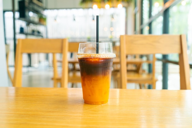 Café negro helado con taza de jugo de yuzu de naranja en la mesa en la cafetería cafetería